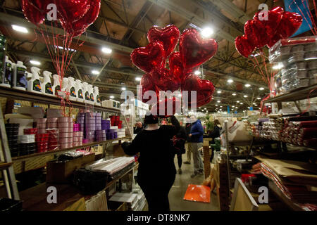 Vauxhall London, UK. 12th February 2014. A trader carries heart shaped balloons in New Covent Garden a few days running up to St Valentines Day. New Covent Garden  Flower Market is London's premier market stocking a wide range of flowers and plants  The British people  are expected spend  more than 50 million pounds on flowers for Valentines with 99 percent on roses Credit:  amer ghazzal/Alamy Live News Stock Photo