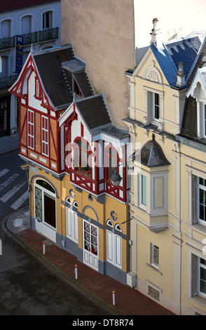 Tiny vintage chalet built onto big residential blocks (Vichy, France). Big building vs little tiny house. Stock Photo