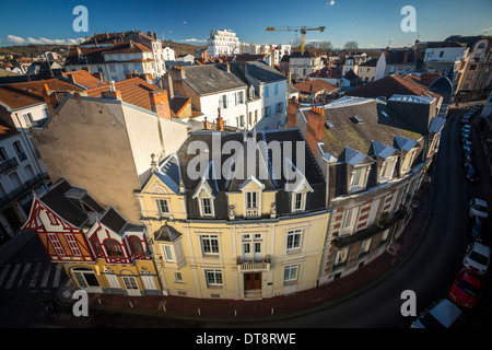 Tiny vintage chalet built onto big residential blocks (Vichy, France). Big building vs little tiny house. Stock Photo