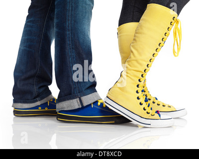 Closeup of woman and man legs in colorful blue and yellow trainers shoes isolated on white background Stock Photo