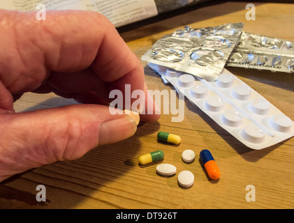 Elderly man's hand with selection of pills, tablets and capsules. Daily dose of medication. Stock Photo