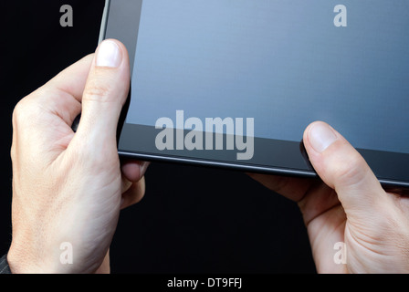 Close-up of a hand holding an unlit tablet, upper right. Stock Photo