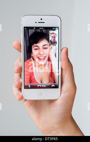 Young woman talking via FaceTime on white Apple iPhone, UK Stock Photo