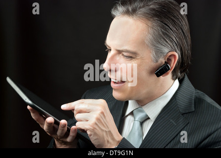 Close-up of a businessman wearing an earpiece headset using a tablet. Stock Photo