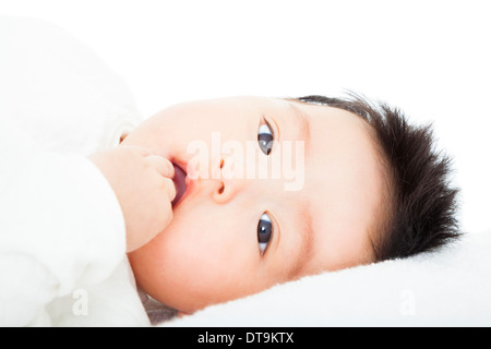 cute baby sucks his thumb lying in bed at home Stock Photo