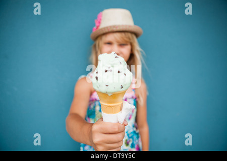 Closeup and focus on vanilla ice cream cone held by cute young girl Stock Photo