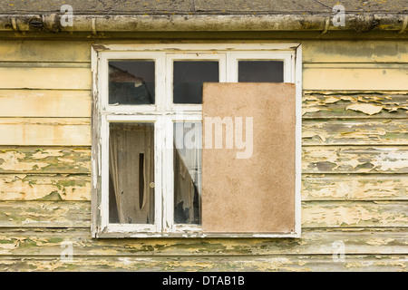 Partly boarded up window in a derelict house Stock Photo