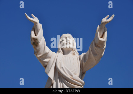 Jesus Christ with hands raised in blessing under blue sky. Marble funerary statue. Stock Photo