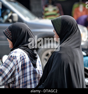 Muslim woman in traditional hijab riding motorcycle. Thailand S. E. Asia Stock Photo