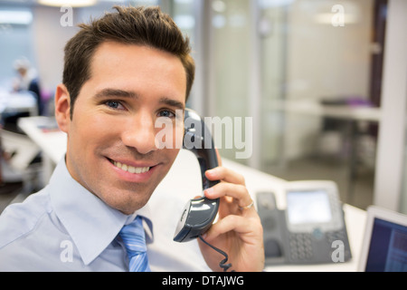 Smiling Businessman on phone in office, looking camera