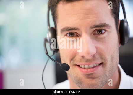 Portrait of businessman in office on phone with headset, looking camera Stock Photo