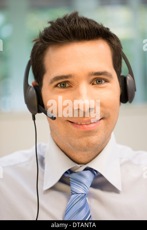Portrait of operator in office on phone with headset, looking camera Stock Photo