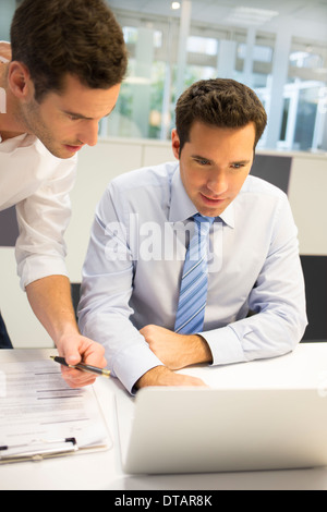 Two handsome businessmen working together on a Laptop in the office Stock Photo