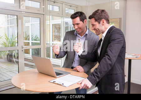 Successful smiling businessmen in office, giving thumbs up Stock Photo