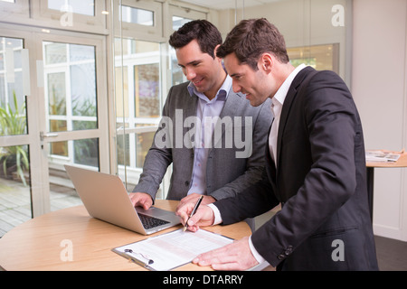 Two casual businessmen working together in modern office with laptop Stock Photo