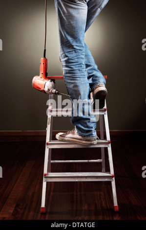 Man working on ladder with drill Stock Photo