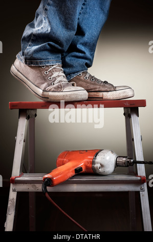 Man working on ladder with drill Stock Photo