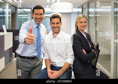 Portrait of joyful business team, man showing thumb up, office background Stock Photo