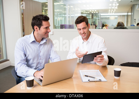 Two casual businessmen working together in office with laptop and tablet pc Stock Photo