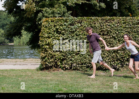 Young couple holding hands and running in park Stock Photo