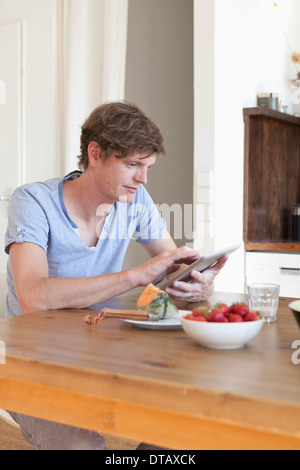 Young man sitting at dining table using digital tablet Stock Photo