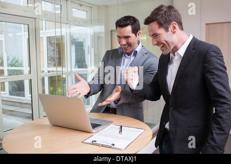 Successful smiling businessman in office, with arms up Stock Photo