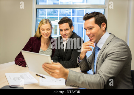 Architect showing a construction project on tablet at young couple, new property owners Stock Photo
