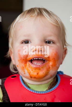 A smiling baby boy with food on his face close-up Stock Photo