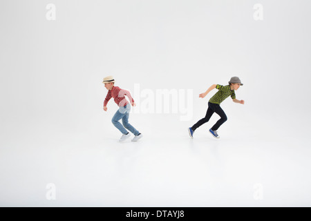 Two boys running opposite direction against white background Stock Photo