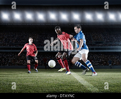 Soccer players with ball on field Stock Photo