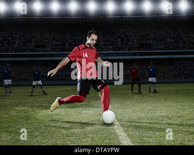 Soccer player kicking ball on field Stock Photo