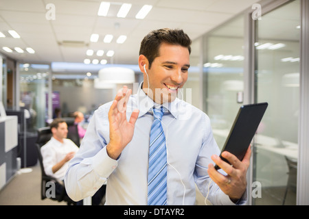 Smiling Businessman chatting on internet with Tablet Pc, office Background Stock Photo