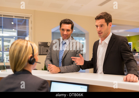 Businessmen communicating with woman receptionist in lobby Stock Photo