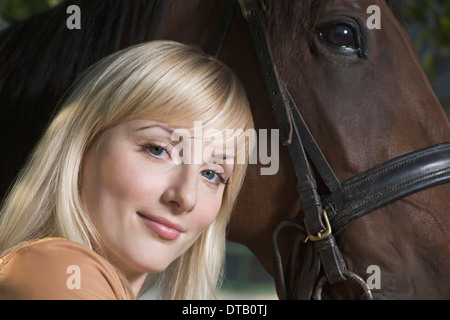 Portrait of young woman with horse, smiling Stock Photo