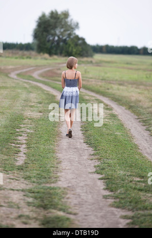 Teenage girl walking on dirt track Stock Photo