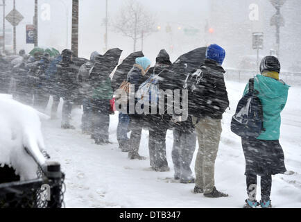 New York, USA. 13th Feb, 2014. People wait for a bus at a bus station in the Queens borough of New York, Feb. 13, 2014. The winter storm moving up from the U.S. southern states has brought heavy snow and freezing sleet to the Northeast on Thursday, closing up federal agencies, schools and airports while leaving half a million people without electricity. A heavy snowfall between 20 to 38 cm is expected in metropolitan areas of Philadelphia, New York and Boston by the end of Thursday. Credit:  Xinhua/Alamy Live News