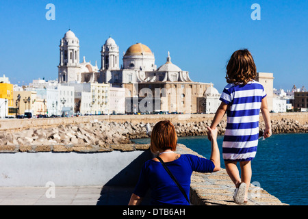 Tourists mother and daughter with blue striped t shirt on the promenade with the Cathedral of Cadiz, Andalusia, Spain Stock Photo