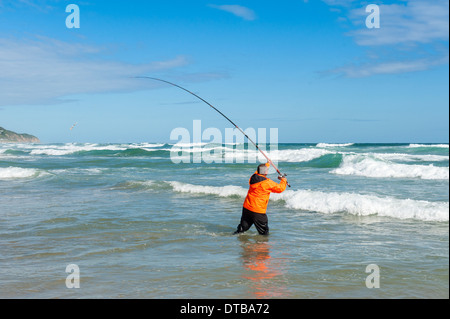 Fisherman casting a fishing rod standing in breaking waves, Sedgefield, Eastern Cape, South Africa Stock Photo