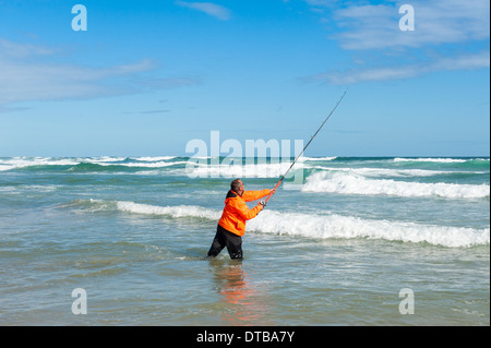 Fisherman casting a fishing rod standing in breaking waves, Sedgefield, Eastern Cape, South Africa Stock Photo