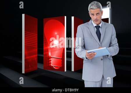 Composite image of serious businessman using tablet pc looking at camera Stock Photo