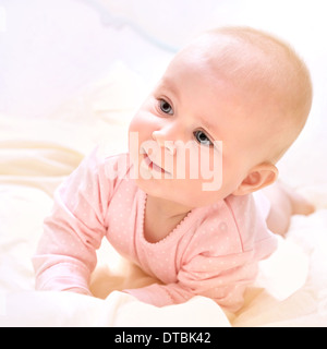 Closeup portrait of cute newborn baby lying down on the bed at home, wearing sweet pink clothes, purity and innocence concept Stock Photo