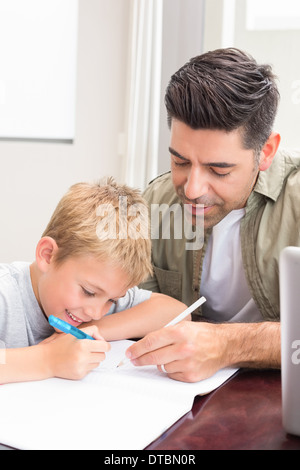 Father and son sitting at table colouring together Stock Photo