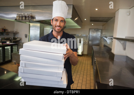 Smiling pizza chef holding stack of pizza boxes Stock Photo