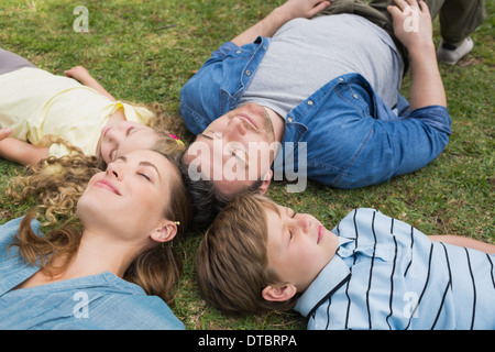 Family lying on grass with eyes closed at park Stock Photo