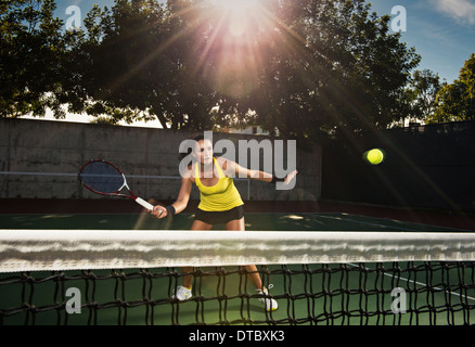 Female tennis player hitting ball over net Stock Photo
