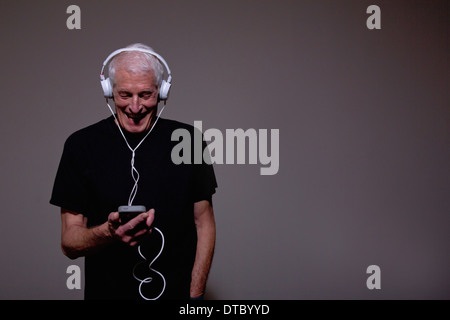 Portrait of senior man wearing headphones and using MP3 player Stock Photo