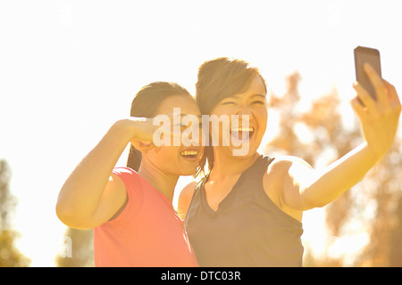 Two young women making self portrait in park Stock Photo