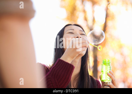 Young woman in park blowing bubbles Stock Photo