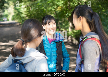 Three young female hikers chatting on country road Stock Photo