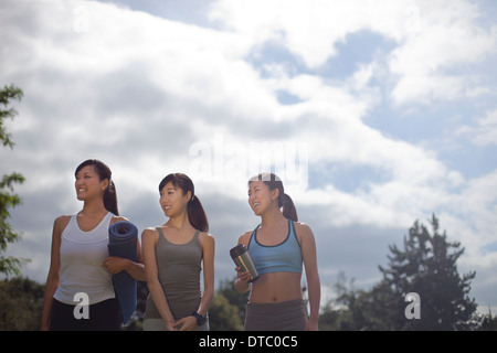 Three young women preparing for yoga in park Stock Photo